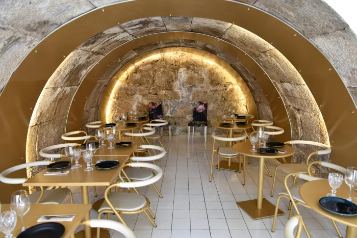 A sala do restaurante sob arcos de granito, com as mesas postas