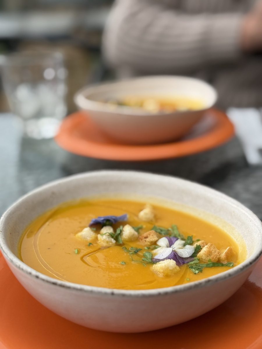 Velouté de légumes aux croûtons et fleurs comestibles, dans un bol en terre cuite