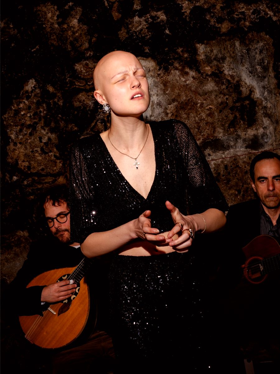 Fadista en paillettes chantant les yeux fermés, entre la guitare portugaise et la viola