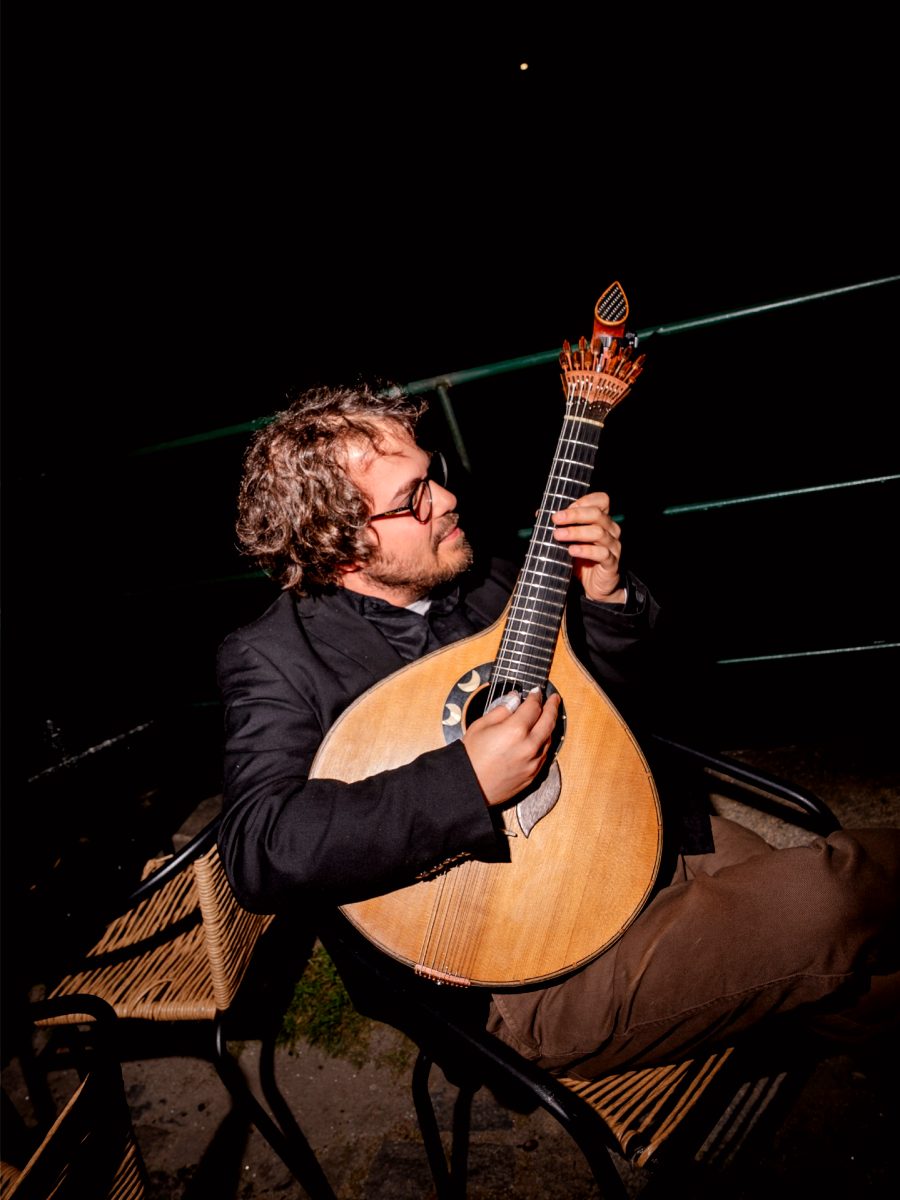 Guitare portugaise sur les genoux du musicien, l’éventail des douze chevilles bien visible